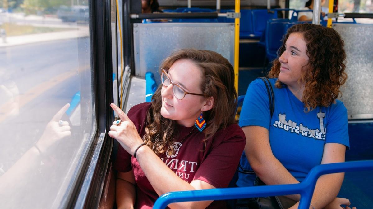 Two students on a bus looking out the window