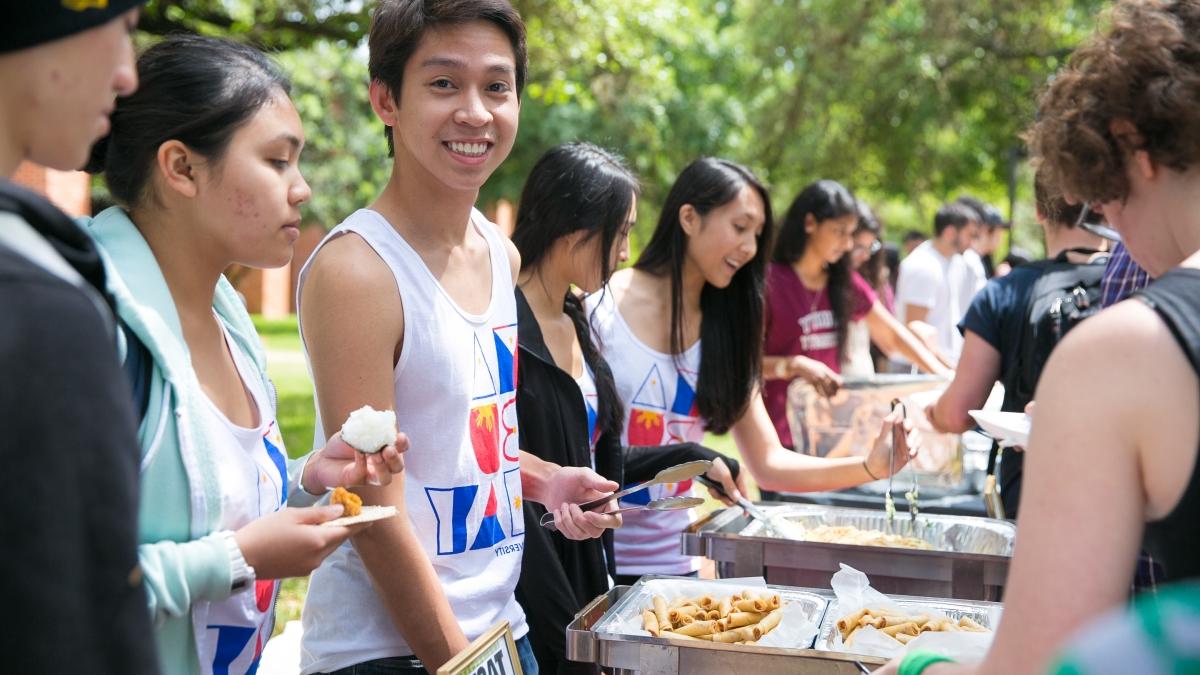 a male student serves food in line at Taste of Diversity